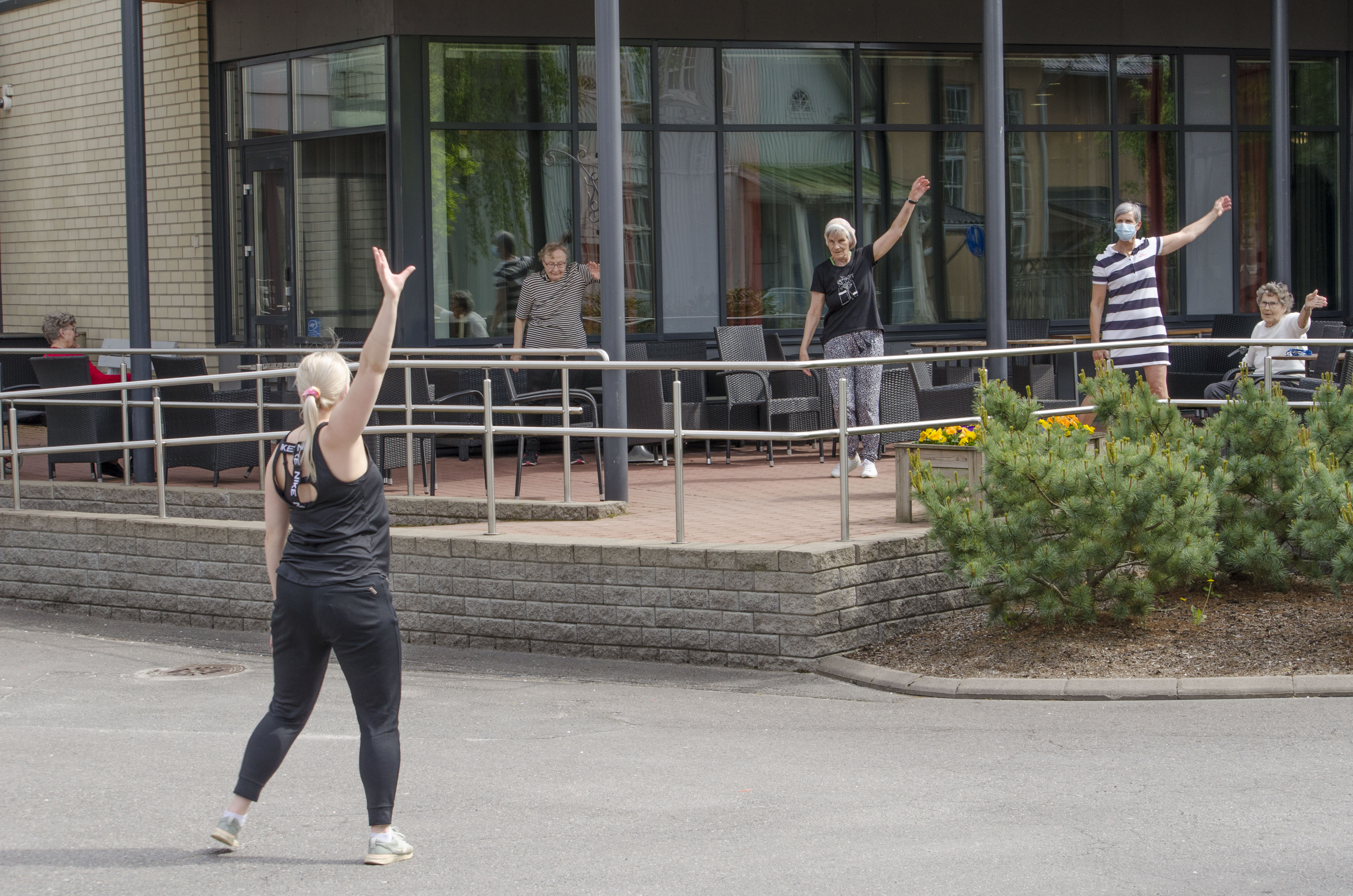 Fysioterapeutti ohjaa ryhmäliikuntaa pihalla