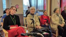 Nuori nainen ja vanhemmat rouvat kuuntelevat musiikkia