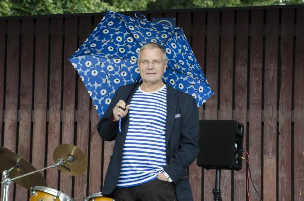 Mies seisoo sateenvarjon kanssa